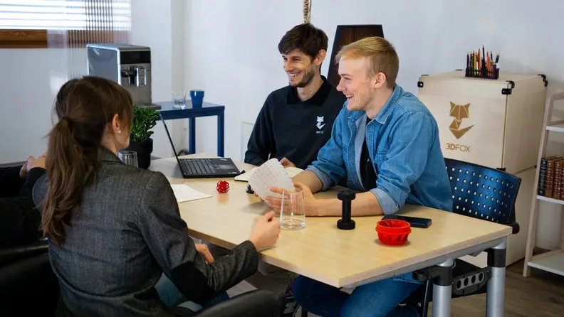 Foto von vier Personen gegenueber am Tisch sprechen ueber 3D Druck Teile