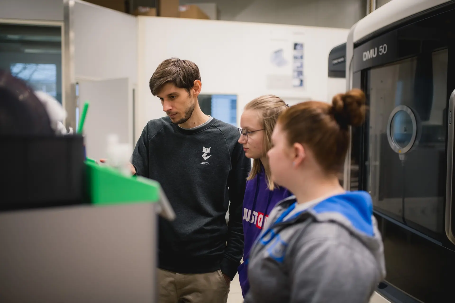 Trainer und Schueler beobachten 3D Drucker